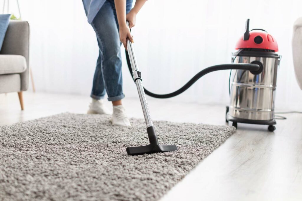 Low section of woman cleaning carpet with vacuum cleaner